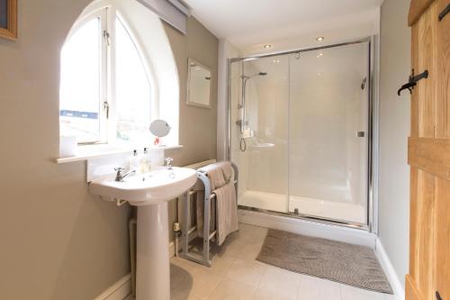 uma casa de banho com um lavatório e um chuveiro em Grooms Cottage em Weedon Bec