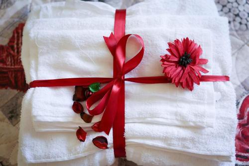 un pastel blanco con una cinta roja y una flor en él en B&B Le Magnolie en Amorosi