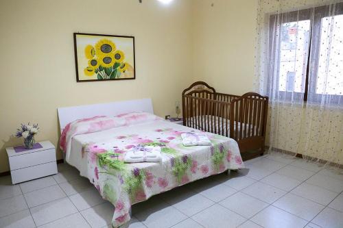 ein Schlafzimmer mit einem Bett mit einem Kinderbett und einem Gemälde in der Unterkunft B&B Le Magnolie in Amorosi