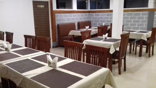 a dining room with tables and chairs with white tablecloths at Olives Pleasant Stays in Ooty