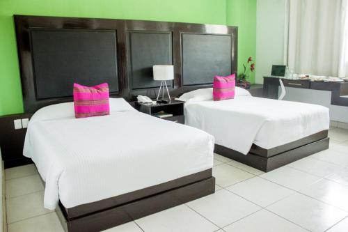 2 camas en una habitación de hotel con almohadas rosas en Chiapas Hotel Express, en Tuxtla Gutiérrez