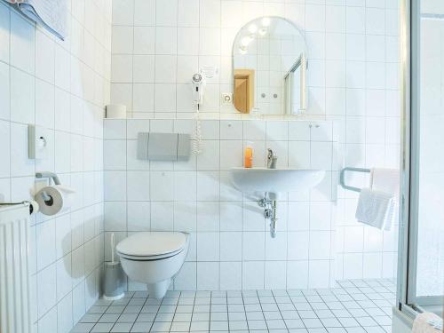 a white bathroom with a toilet and a sink at Gästehaus Mönchshof in Sommerhausen