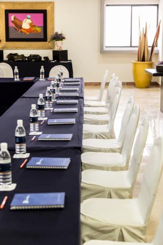 a row of tables with white chairs and bottles of water at Imperio de Angeles Executive León Poliforum in León