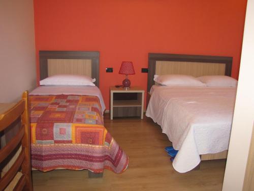 two beds in a room with orange walls at Joan Guesthouse in Përmet