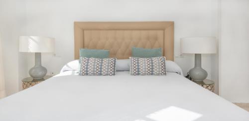 a bedroom with a white bed with two lamps at Myramar Premium Center in Málaga
