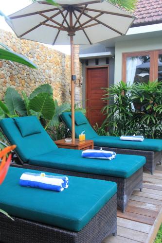 a patio with blue chairs and an umbrella at Uma Karan in Seminyak