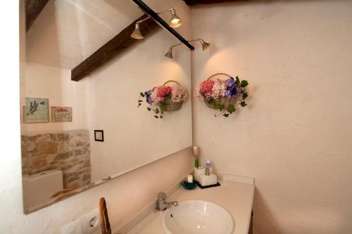 a bathroom with a sink and a mirror and flowers at La Covarxella in Culla