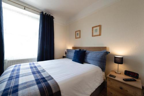 a bedroom with a bed with blue pillows and a window at Blue Swallow in Penrith