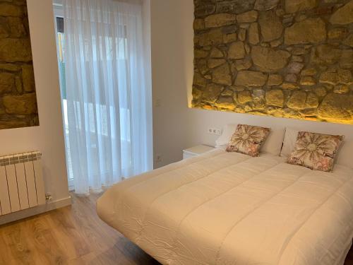 duże łóżko w pokoju z kamienną ścianą w obiekcie ARENA Apartamento - Perla Boutique Apartamentos w mieście San Sebastián
