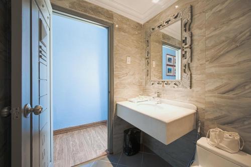 a bathroom with a sink and a mirror and a toilet at A&EM - The Petit Hotel in Ho Chi Minh City