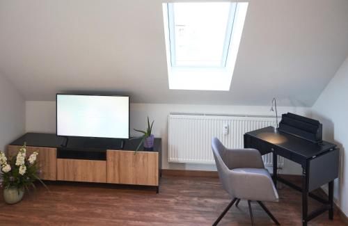 a living room with a tv and a desk and a piano at Airport & Messe Apartments in Hannover