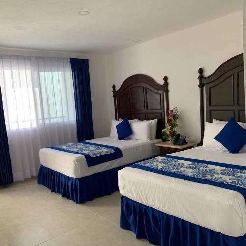 two beds in a hotel room with blue and white at Hotel Catedral Valladolid Yucatan in Valladolid