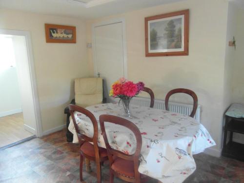 a dining room table with a vase of flowers on it at Country Cottage in Portarlington