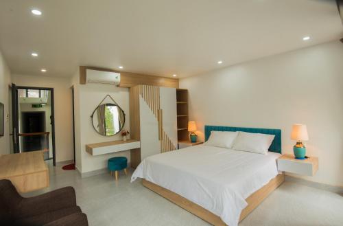 a bedroom with a bed and a chair and a mirror at Kim Phu Villa Hoi An in Hoi An