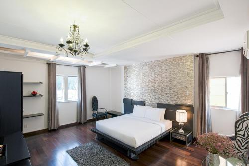 a bedroom with a bed and a couch and a chandelier at A&EM - The Petit Hotel in Ho Chi Minh City
