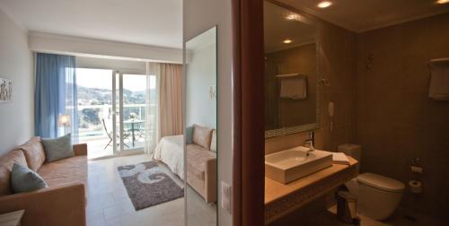 a bathroom with a sink and a toilet and a couch at Odysseus Hotel in Paleokastritsa