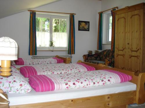 sypialnia z dużym łóżkiem z fioletową i różową pościelą w obiekcie Gästehaus Alpenland w mieście Halblech