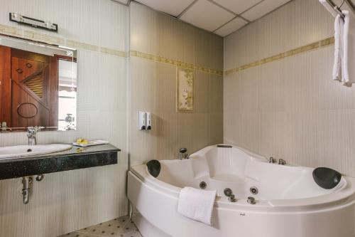 a white bathroom with a tub and a sink at Sophia Hotel in Ho Chi Minh City