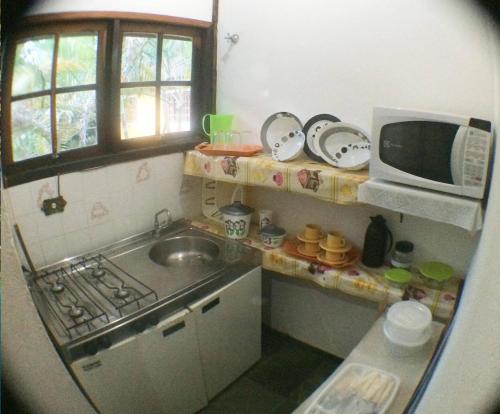 a small kitchen with a sink and a microwave at Condomínio Boiçucanga in Boicucanga