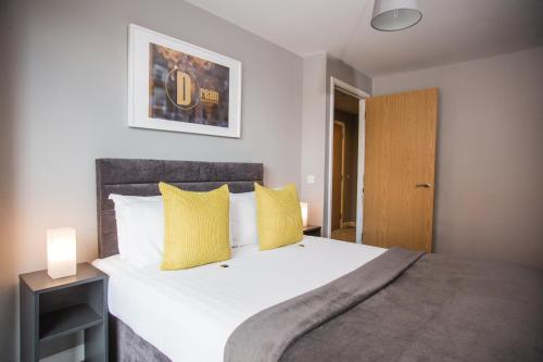 een slaapkamer met een groot bed met gele kussens bij Dream Apartments Belfast in Belfast