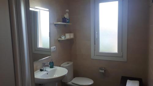 a bathroom with a toilet and a sink and two windows at Barrañán Arena in Arteixo