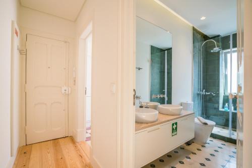 リスボンにあるLiberdade Apartmentのバスルーム(洗面台2台、ガラス張りのシャワー付)