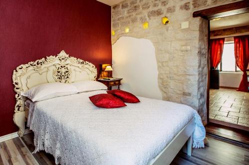 a bedroom with a white bed with red pillows at Villa Residence Burgus-Antium in Trogir