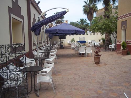 an outdoor patio with tables and chairs and umbrellas at Riad Taroudant Palmiers in Taroudant