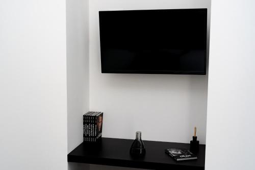 a television on a white wall with a black table at White Rooms in Reggio Calabria