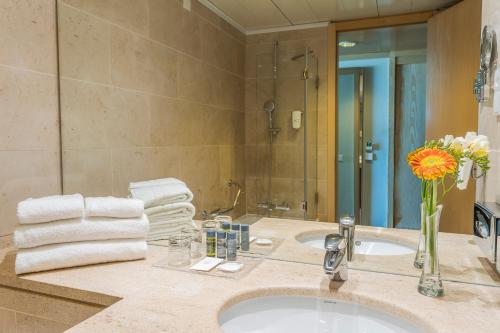 un lavandino in bagno con vaso di fiori e asciugamani di HF Ipanema Porto a Porto