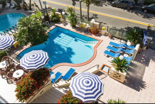 uma vista sobre uma piscina com guarda-sóis e cadeiras em Hotel Cobalto em Rimini