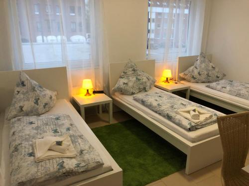 a room with three beds and two lamps on tables at Pension Laatzen in Hannover