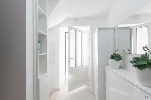 un couloir blanc avec des plantes en pot et des miroirs dans l'établissement Holiday Home Revelin- Great Location, à Dubrovnik
