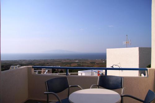 a balcony with a table and chairs and the ocean at Olympic Villas in Oia