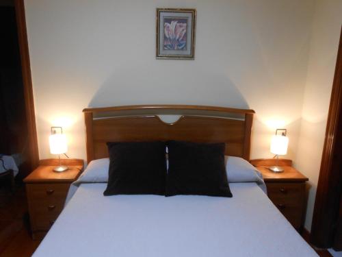 a bedroom with a white bed with two lamps on tables at La Bolerina in Celorio