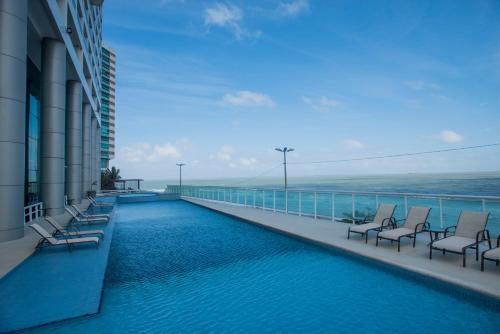 uma varanda do hotel com cadeiras e uma piscina em Hotel Luzeiros São Luis em São Luís