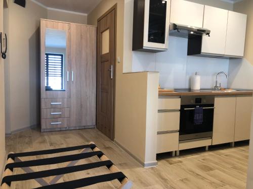 a kitchen with white cabinets and a wooden floor at Apartamenty ALICJA in Dzierżoniów