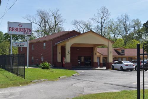 a red brick building with a sign in a parking lot at Residents Suites Liberty in Liberty