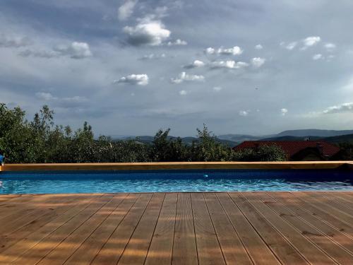 a swimming pool with a wooden deck and a cloudy sky at Pensjonat Zacisze in Czchów