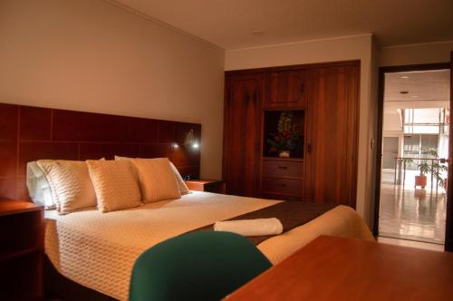 a bedroom with a large bed with a wooden headboard at Hotel San Ignacio Plaza in Tunja