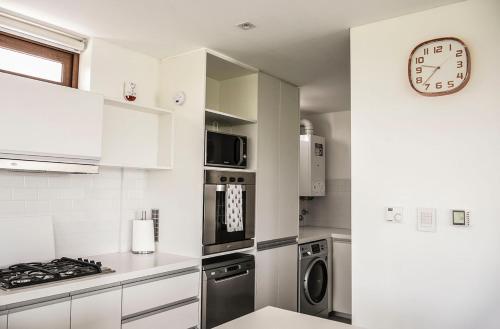 a kitchen with white cabinets and a clock on the wall at Aizarker in La Plata