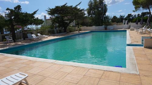 una grande piscina con sedie e alberi in un cortile di Villa Anna a SantʼAndrea
