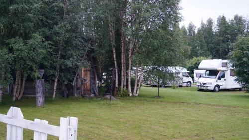 a white fence in front of a field with trees at Holiday Village Kuukiuru in Vuostimo