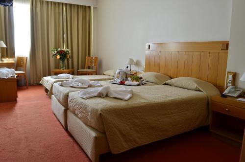 a hotel room with three beds with towels on them at Ilissos in Athens