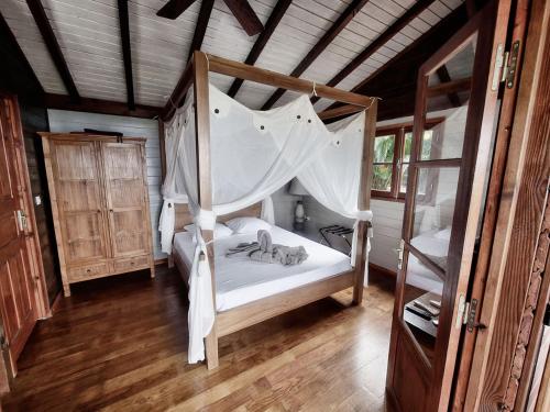 a bedroom with a canopy bed and a wooden ceiling at karureve in Deshaies