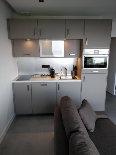 a kitchen with white cabinets and a couch at Les Gîtes du Cap Cod in Varengeville-sur-Mer