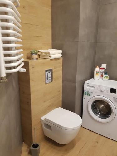 a bathroom with a toilet and a washing machine at Caskada Modern Apartment in Słupsk