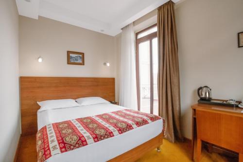 a bedroom with a bed and a desk and a window at Urban Boutique Hotel in Tbilisi City