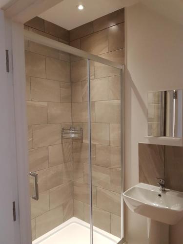 a shower with a glass door next to a sink at Charlie Mews in Farnborough