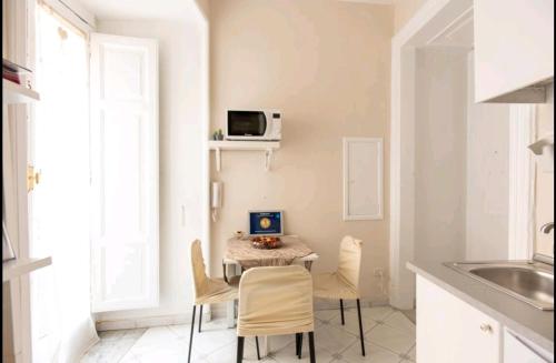 kuchnia ze stołem, krzesłami i kuchenką mikrofalową w obiekcie Borgo Santa Lucia Apartment w mieście Neapol